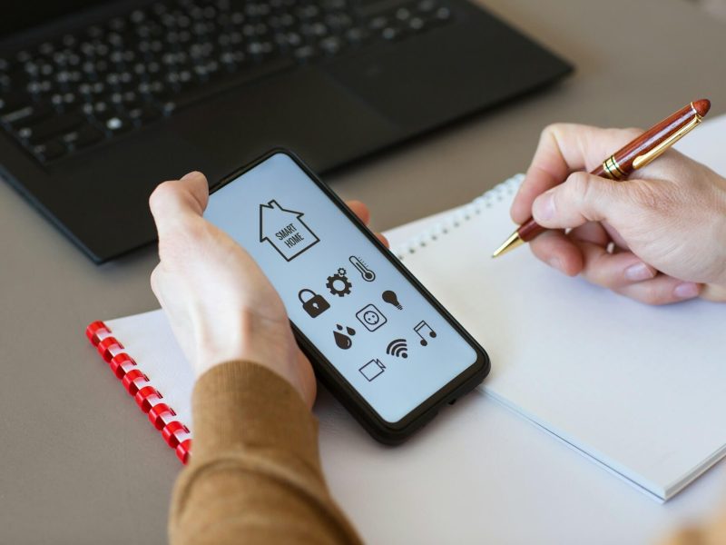 man-controls-smart-home-devices-using-app-for-mobile-phone-on-background-of-businessman-s-work-table.jpg